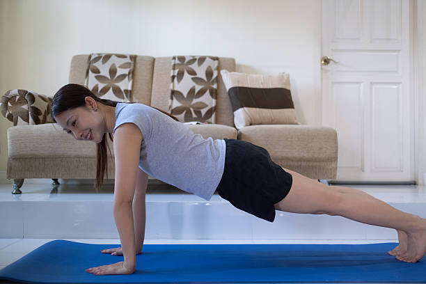 istock A woman is doing a plank on a blue mat in a living room 2246367405