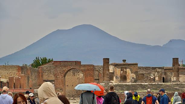 Pompeii Italy Oct 15, 2025 Tourists walking in the marble Forum of Pompeii .  Mt Vesuvius issilhouetted in the background