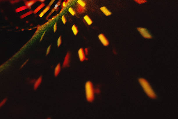 Vibrant orange and yellow lights streak across a shadowy surface, creating a glowing abstract design.