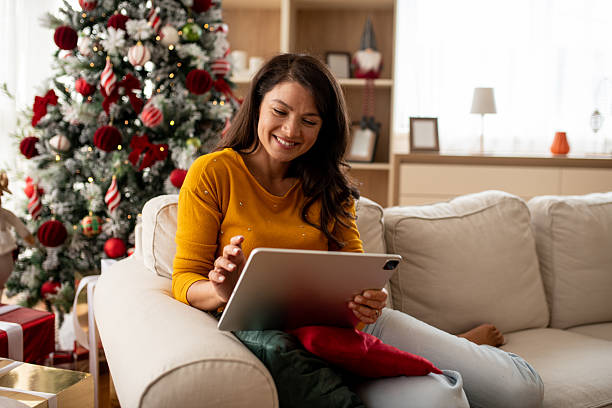 istock Smiling woman using tablet near Christmas tree 2246375790