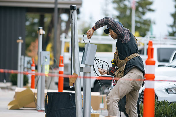 An EV charge station technician works diligently at putting in a new charging point access for environmentally friendly clean energy.  Shot in Washington state.