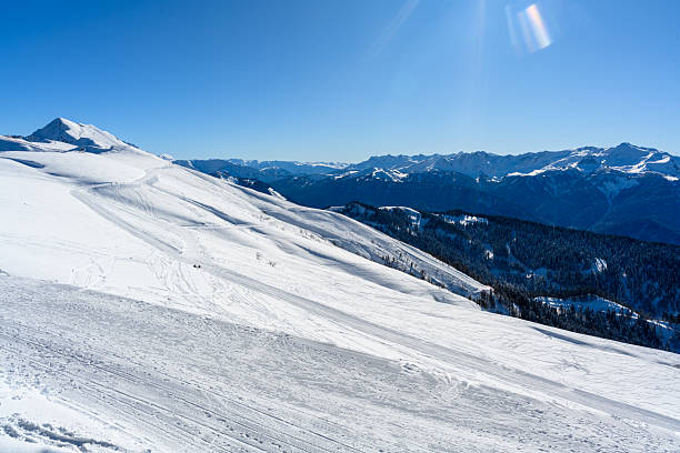 The slope of the mountain. In the foreground there are beautiful snow-capped mountains and an opening view of the valley. The bright winter sun highlights the snow-white landscapes.