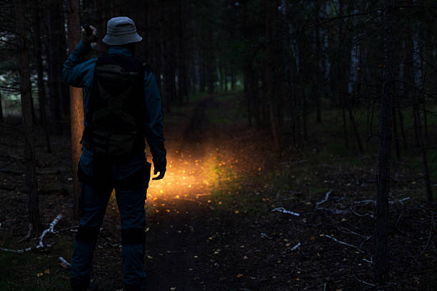istock A man with a panama hat is walking along a path and shining a flashlight in front of him 2246389599
