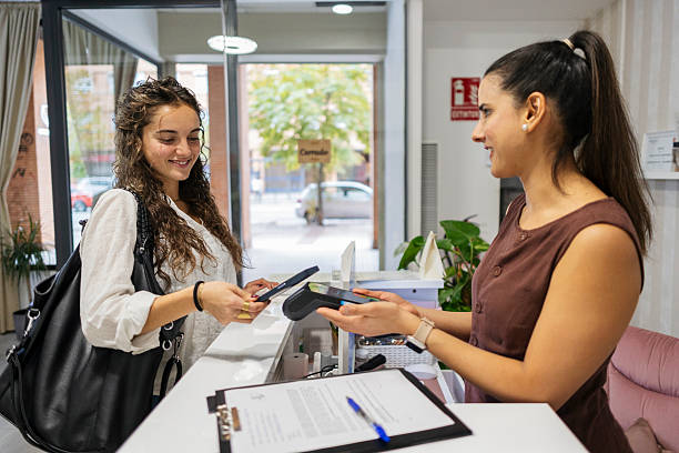 istock Woman making contactless payment using smartphone at reception 2246389829
