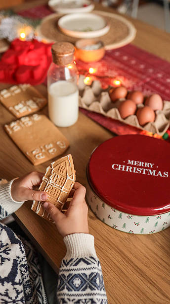 istock Child decorating a gingerbread house with icing at a Christmas table setting 2246390103