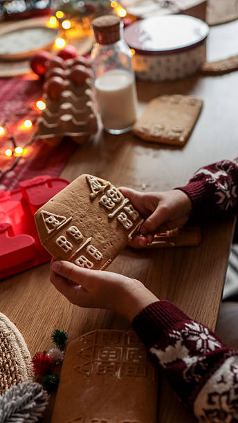 istock Child decorating a gingerbread house with icing at a Christmas table setting 2246390104
