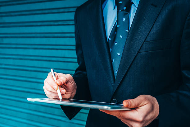 istock Businessman in suit using tablet device, close-up 2246391123