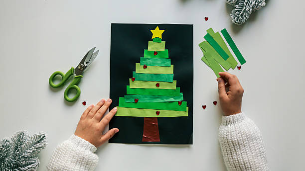 istock Child's handmade Christmas tree craft on black paper with scissors and decorations 2246392149