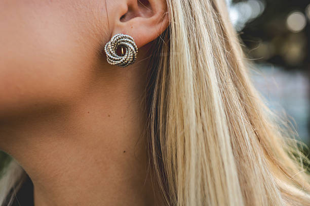 istock Close-up of a woman's ear with a beautiful silver stud earring 2246394090