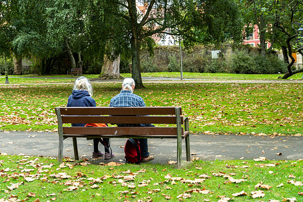 A woman and her son are walking through an autumn park, collecting yellow leaves.