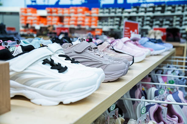 istock Assorted sneakers neatly arranged on a store shelf, showcasing various styles and colors. The footwear range includes white, pink, and gray options, offering diverse choices for customers. 2246397299