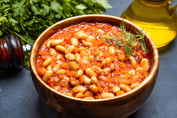 istock Baked bean dish in wooden bowl on black background. 2246401717