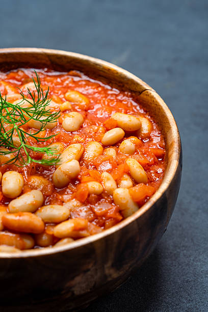 istock Baked bean dish in wooden bowl on black background. 2246401773