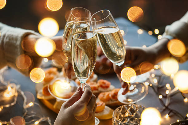Friends celebrating Christmas or New Year eve party with champagne or sparkling wine. stock photo