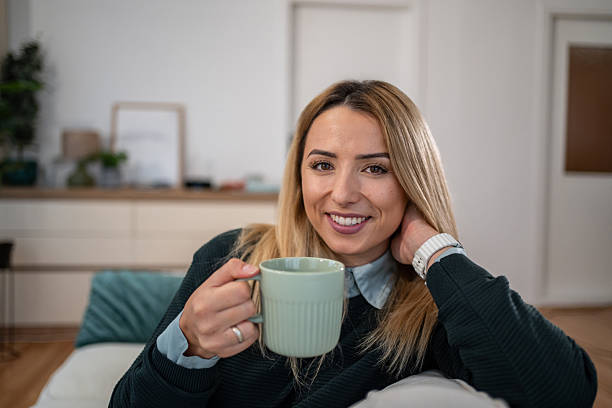 istock Woman smiling holding coffee mug relaxing home 2246415490