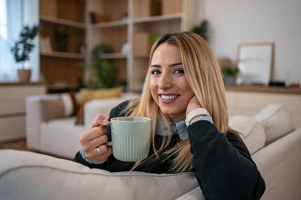 istock Woman relaxing on couch enjoying coffee at home 2246415512