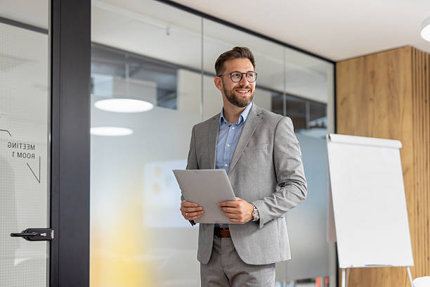 istock Businessman holding documents and smiling in modern office 2246428906