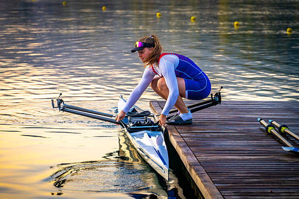 Silhouette of young man rowing on river