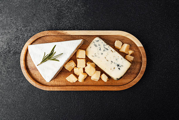 istock Delicious cheese platter with assorted cubes and wedge on wooden board 2246429927
