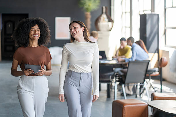 istock Two young businesswomen walking and talking in modern office 2246430728