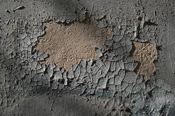 An old wall with peeling paint displaying cracked and damaged surface, indicating deterioration and need for repair.