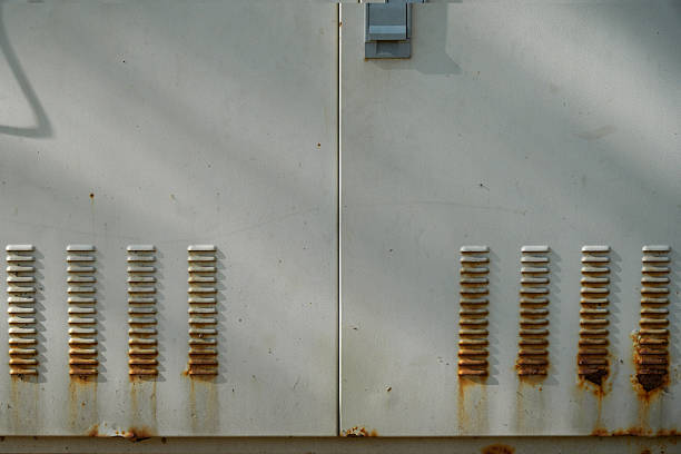 Close-up shot showing rusty ventilation slots on a metallic panel, highlighting corrosion and surface texture.