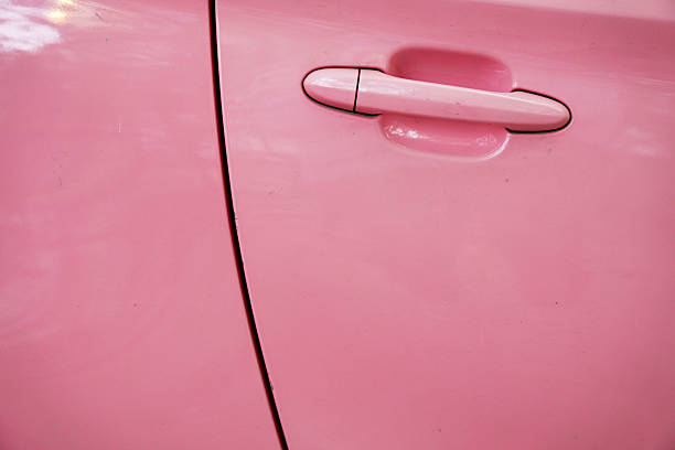 A close-up shot showing the pink car door handle with its sleek and shiny appearance.