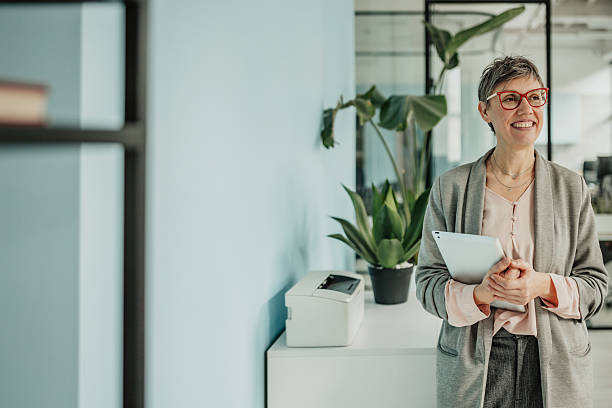 istock Businesswoman smiling while holding a clipboard in a modern office setting with plants and natural light 2246438583