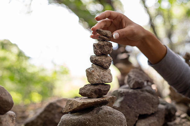 Female hand stacking and balancing stones in a forest, close up