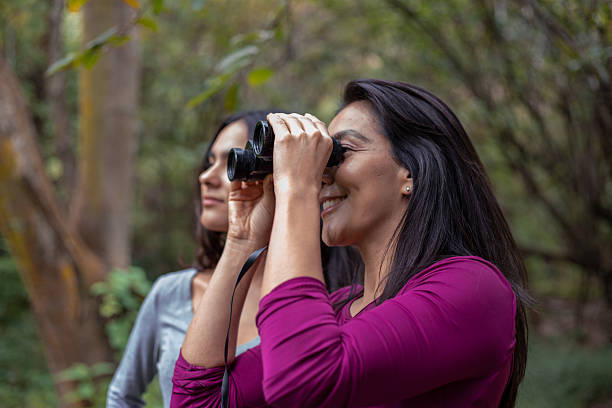 istock Hispanic mother and daughter using binoculars in forest 2246444024