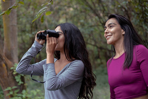 istock Hispanic mother and daughter using binoculars in forest 2246444035