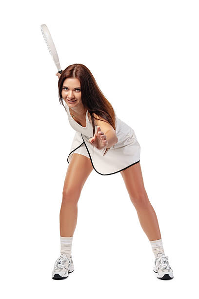 A young woman in a tennis outfit is ready to serve with a racquet in hand.