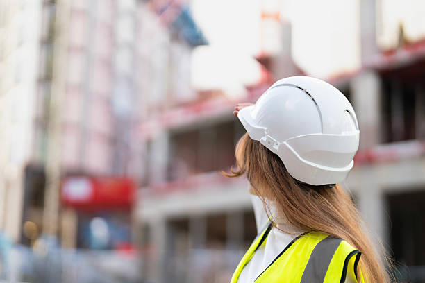 istock Woman builder in white helmet observes building progress at construction site 2246454478