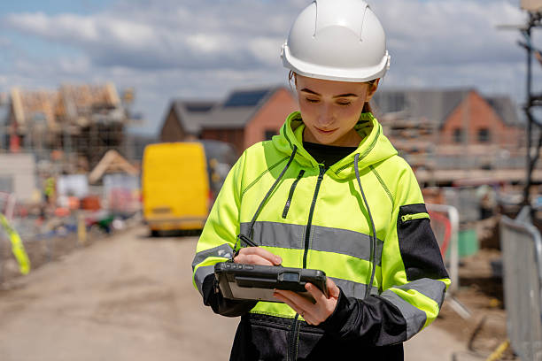 istock Young woman construction worker checks plans on portable computer tablet at building site 2246454481