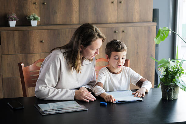 istock Mother helping her little son doing his homework at home 2246458021