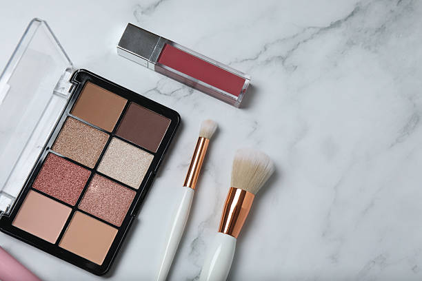 istock Cosmetics on a marble background. Cosmetic palette, brushes, creams and lipsticks. Top view. 2246461503