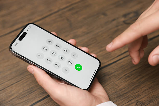 istock Man dialing number on smartphone at wooden table, closeup 2246462873
