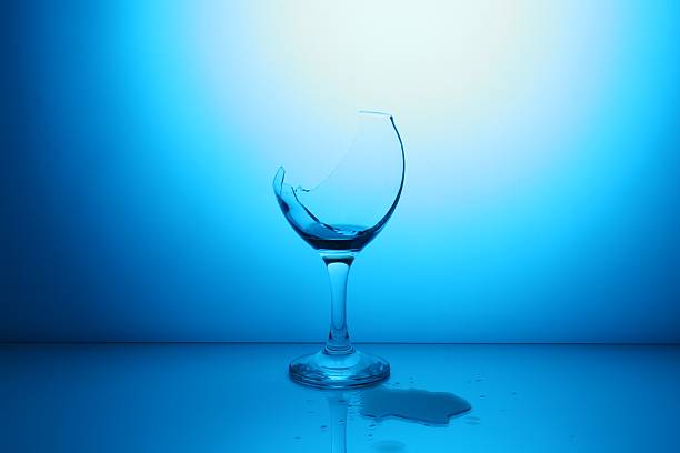 istock Broken glass with spilled wine against light blue gradient background 2246463381