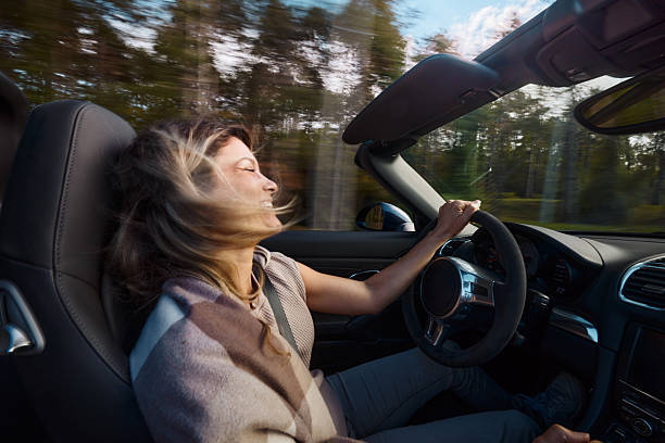 istock Happy woman driving a convertible car in blurred motion. 2246467708