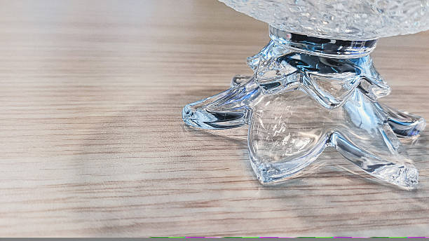 Close-up of an elegant crystal bowl stand's intricate base on a wooden surface.
