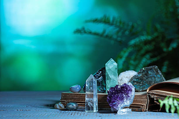istock Beautiful natural gemstones and book on grey table against green background. Space for text 2246471392