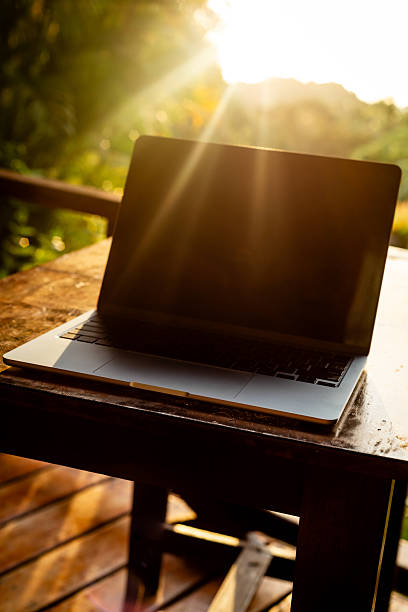istock Laptop with backlight on wooden table on terrace in tropical forest at sunset, remote work digital nomad 2246471426