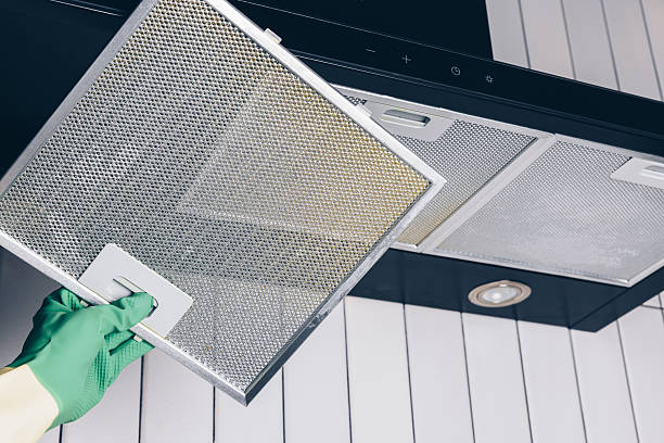 istock Woman's hand removing a filter from cooker hood for cleaning or service. Replacing filter in kitchen hood. Professional cleaning kitchen hood with rag 2246472179