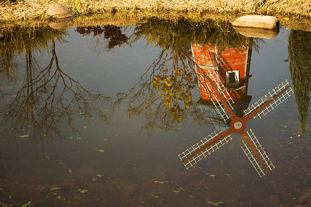 .Reflections of windmills and trees in a calm autumn pond.