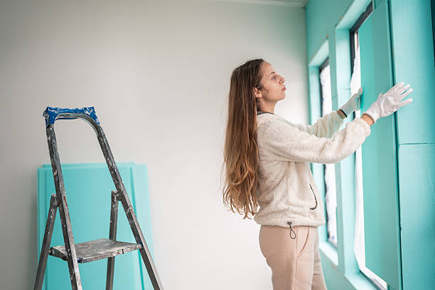 Young housewife wearing gloves and cleaning clear glass in a modern home. Concept of household cleaning and home organization.