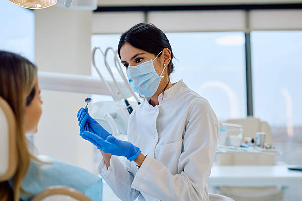 istock Dentist holding dental mirror for patient oral exam 2246474082