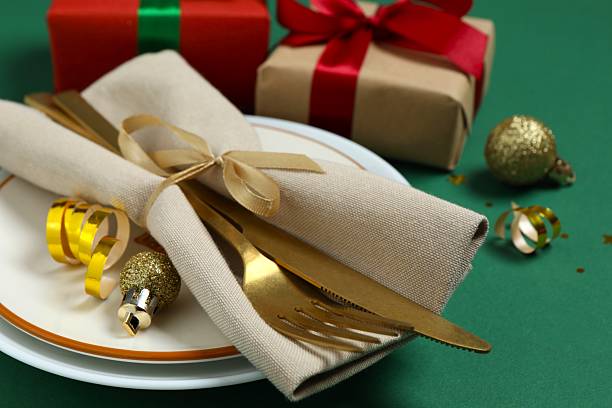 Festive Christmas and New Year's tablescape with pine branches, red ornaments and elegant dinnerware on dark background. Perfect for holiday greetings