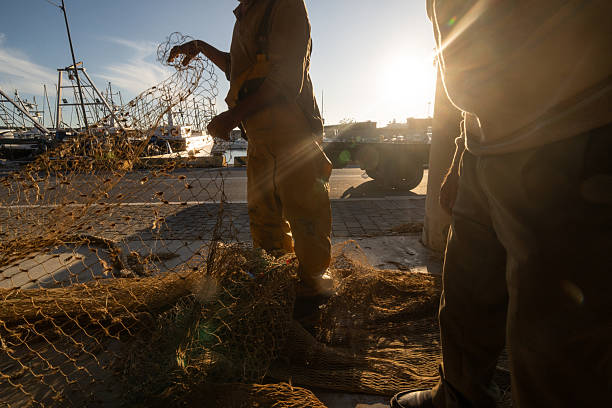 istock Fishermen repairing nets at sunrise in a Mediterranean harbor 2246475664