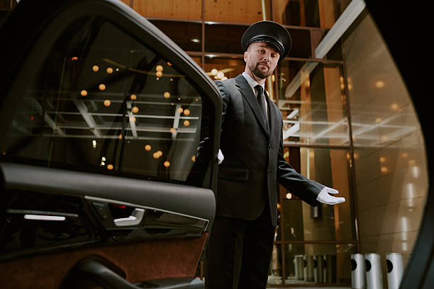 istock Middle Aged Man Wearing Uniform Opening Car Door for Client 2246478916