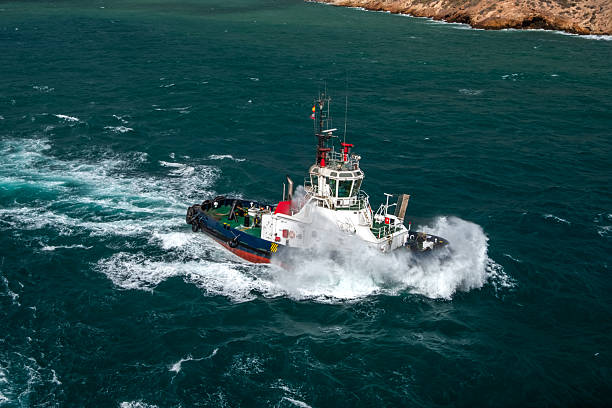 A tugboat moving at speed escorting a cruise ship out of the harbour.